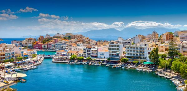 Scenic view of a Greek coastal town with colorful buildings and boats in a harbour.
